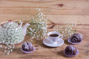 Cup of coffee and chocolates on a wooden table.