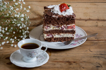 Chocolate cake with strawberries and cup of coffee on a wooden background
