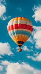 Fototapeta premium Striped hot air balloon drifting across a clear blue sky with fluffy clouds