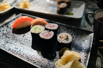 Delicious sushi assortment including salmon, tuna and eel varieties, captured in traditional Japanese restaurant atmosphere.