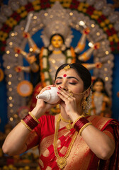 Durga Puja women in red sari with conch