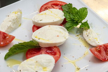 Fresh Caprese appetizer showcasing sliced tomatoes, creamy mozzarella, and green basil on a rustic dish