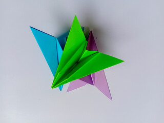 Green, blue and purple plane origami on white background.