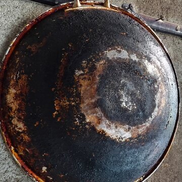 A Heavily Used and Burned Griddle, The Unfortunate Result of Neglect in the Kitchen, A Top-Down Shot Showing a Griddle Covered in Layers of Built-Up Grease