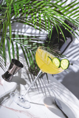 Enjoy cucumber gimlet cocktail drink with gin, syrup, lime juice and cucumber wheels. Marble table...