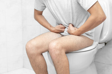 Sitting on toilet with suffering from constipation or hemorrhoid. Feels uncomfortable in his...