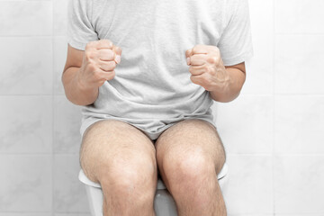 Sitting on toilet with suffering from constipation or hemorrhoid. Feels uncomfortable in his...