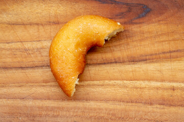 A half-eaten Donat Gula (sugared doughnut) is propped on a fork, resting on the rim of a black...