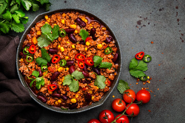 Tex-mex meet chili con carne with beef, red beans,, sweet corn, cilantro in frying pan, rusty green background top view