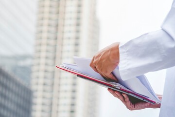 Portrait Islamic man smile working outdoor holding file folder using smartphone digital tablet muslim dress in modern uae city. Saudi Arab men wear hijab Headscarf muslim formal dress lifestyle