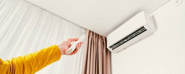 Wall-mounted inverter air conditioner or white split system, female hand sets the temperature with...