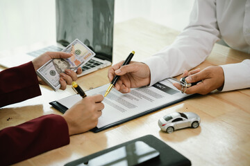 A car salesman hands over keys to a customer, symbolizing agreement, contract, purchase, rental, or...