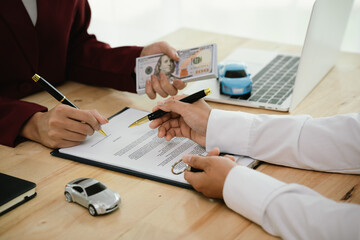 A car salesman hands over keys to a customer, symbolizing agreement, contract, purchase, rental, or...