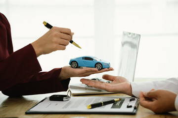 A car salesman hands over keys to a customer, symbolizing agreement, contract, purchase, rental, or...