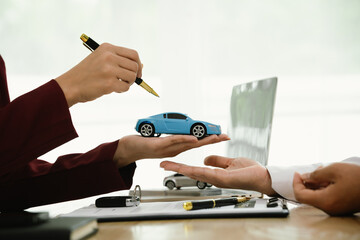 A car salesman hands over keys to a customer, symbolizing agreement, contract, purchase, rental, or...