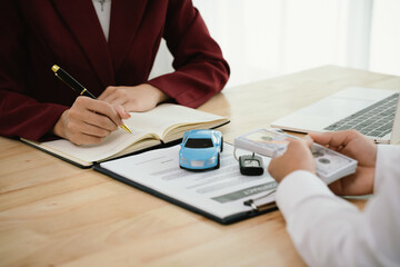 A car salesman hands over keys to a customer, symbolizing agreement, contract, purchase, rental, or...