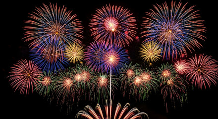 Fototapeta premium A spectacular display of vibrant multicolored fireworks exploding in brilliant spherical bursts against a dark background.