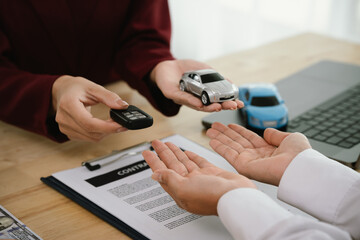 A businessman and client complete an agreement by signing documents for car insurance, loan, or...