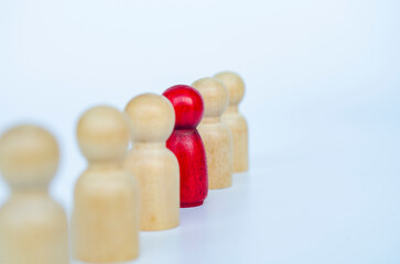 A red figure aligned with other wooden figures, representing leadership or marginalization or...