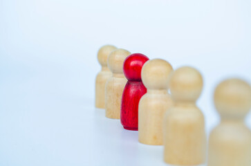 A red figure aligned with other wooden figures, representing leadership or marginalization or...