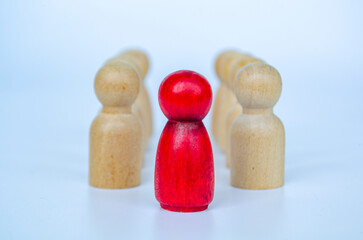 A red figure in front of wooden figures symbolizing leadership or authority or influence concept