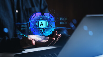Human hand holding AI brain hologram near laptop in dark tech environment.
