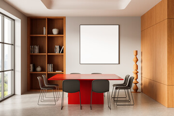 Modern meeting room interior with red table, chairs, and blank poster mockup on wall in wooden...