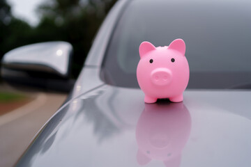 Pink piggy bank on a car hood represents saving money for car purchase, finance, investment, and...