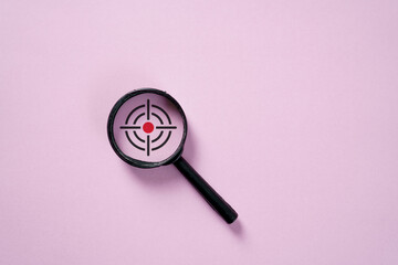 Magnifying glass with crosshair target symbol on pink background, representing, goal targeting,...