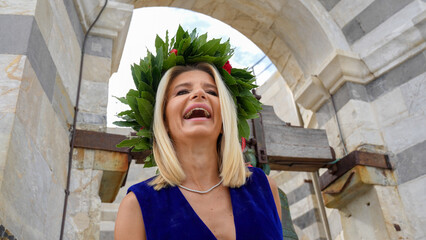 Proud graduate girl celebrating academic success with laurel garland near Pisa Tower landmark
