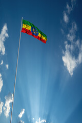 Waving National flag of Ethiopia on flagpole in sky