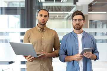 Dynamic collaboration of two professionals standing in a modern office, showcasing teamwork and technology use in a business environment.