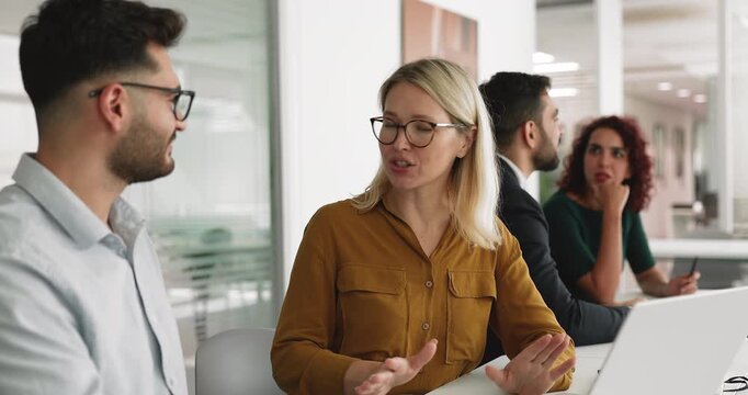 Two friendly multiethnic business partners shaking hands at workplace table with laptop, start partnership, conclude agreement, finalize teamwork successfully, thank each other for productive workflow