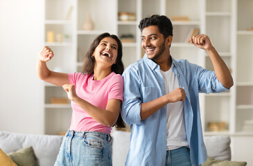 Joyful hindu spouses dancing in living room interior at home, happy indian couple having fun and...