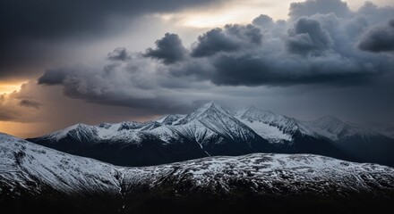 Mountain range under dramatic stormy sky. Snow-capped peaks rise against a backdrop of dark, brooding clouds illuminated by a vibrant sunset. The lower slopes are partially covered in snow