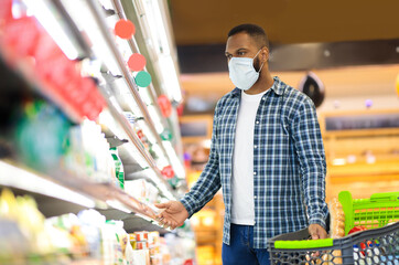 Panic Buying During Pandemic. Black Man Shopping In Supermarket Buying Food Wearing Face Mask, Guy...