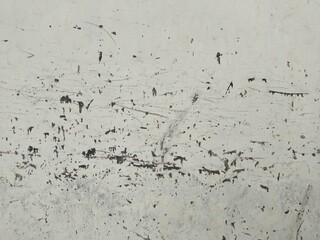 The wall surface is off-white or light gray, dull, and appears old, with numerous visible stains...