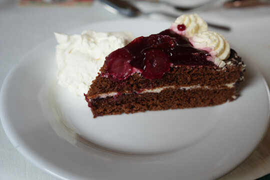 Nottingham Princess, England – August 16 2025: Close-up of a chocolate cherry gateau slice with whipped cream on a white plate