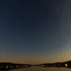 Fototapeta premium Starry Night Sky Over Lake with Meteor Streak