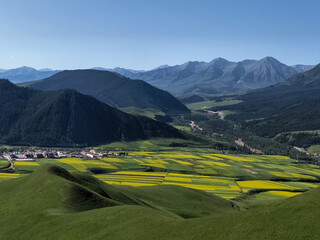 Layered farmland and forest-covered hills with distant mountains,Qinghai China summer view,village...