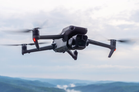 DJI Mavic 3 pro quadcopter on a cloudy sky background . Drone captures stunning aerial view of mountain landscape while flying over lush valleys and misty peaks during golden hour