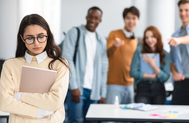 Bullying Concept. Rude diverse group of people mocking and making fun of sad woman in eyeglasses,...