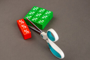 Interest rate cuts. Reducing interest rates. Business concept. Scissors cutting the symbol of interest rates, copy space, grey background