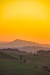 Wonderful orange sunset and sky in Italy in summer over the green gentle hills: amazing panorama.