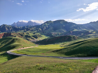 Panoramic view of green valley and hills with temple flags,Qilian Mountains,China,sunny summer rural scenery with colorful cultural elements,tourism and nature landscape