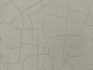 a dull white or light gray wall surface that has a large crack pattern with sharp and curved corners