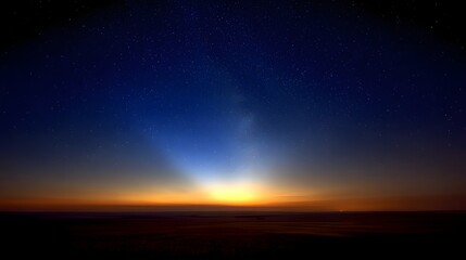 Fototapeta premium A breathtaking sunrise paints the vast expanse of the sky with vibrant colors, while countless stars glimmer in the darkening night above.