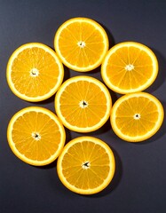 Obraz premium Orange slices arranged on dark background