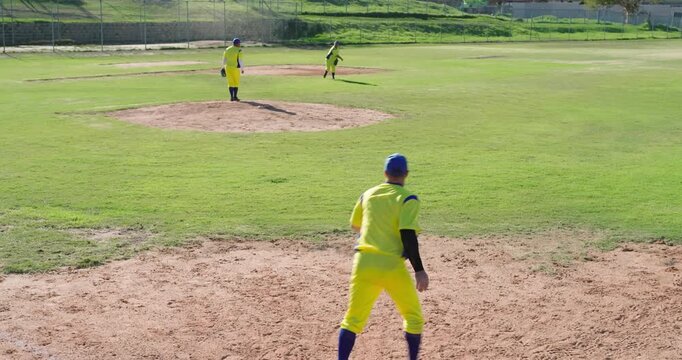 Male pitcher picking off runner at first base and male teammates celebrating on infield, copy space