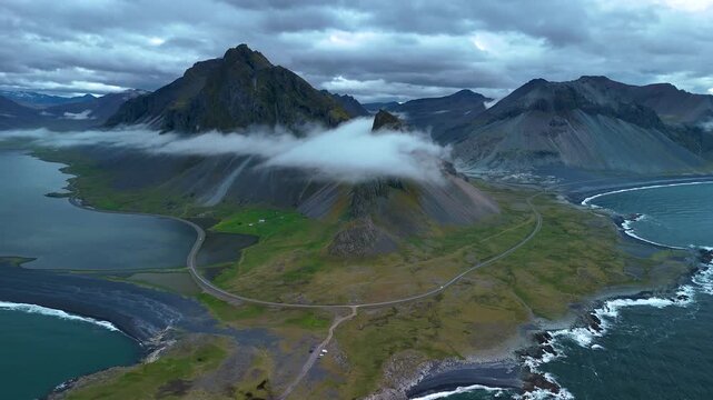 Explore the stunning beauty of Hvalnes Icelands unique landscapes, featuring towering mountain peaks shrouded in clouds and serene waters reflecting the dramatic terrain. A perfect escape into nature.
